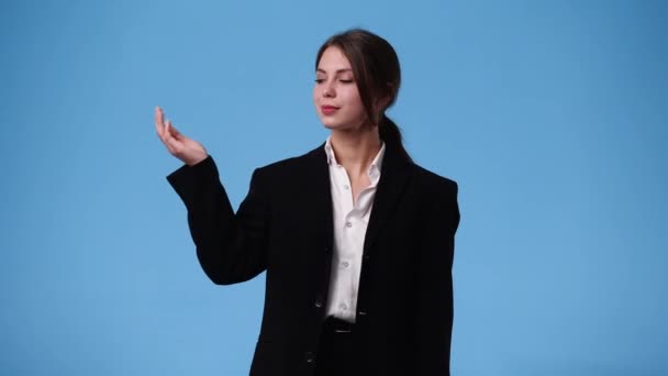 1人の女の子が左を向いて親指を青の背景の上に見せる4Kビデオ 感情の概念 — ストック動画