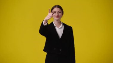 Sarı arka planda kameraya bakan bir kızın 4K videosu. Duygu kavramı..