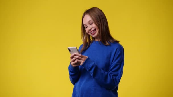 Vídeo Uma Garota Que Digita Texto Telefone Sorri Sobre Fundo — Vídeo de Stock