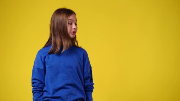 4K慢镜头 一个女孩指着右边 在黄色背景上伸出大拇指 情绪的概念 — 图库视频影像