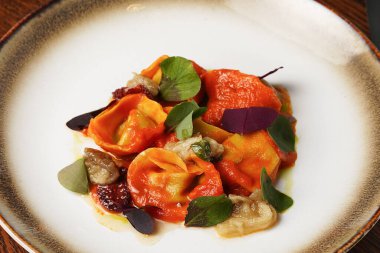 Domates soslu zarif makarna tabağı ve altın kaplamalı otlar.