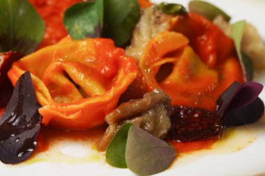 Domates soslu zarif makarna tabağı ve altın kaplamalı otlar.