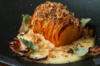 Altın-Kahverengi Hasselback Patatesleri, mantarlı ve siyah tabakta otlu.