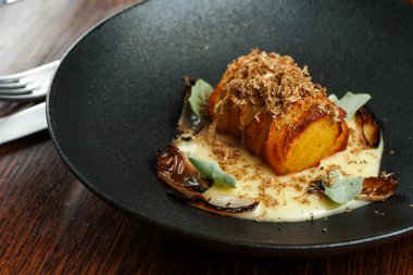 Altın-Kahverengi Hasselback Patatesleri, mantarlı ve siyah tabakta otlu.