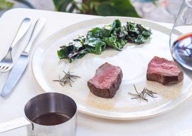 Orta pişmiş biftek, patates Gratin ve Herb Garnish tabakta.