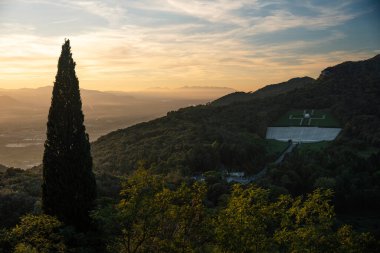 A panoramic view of a mountain range during sunrise or sunset, with soft lighting and warm hues in the sky clipart