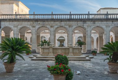 Merkezi çeşmeli, kemer sütunlarıyla çevrili sakin bir avlu. Avlu taş kiremitlerle döşelidir ve büyük eğrelti otları ve çiçek bitkileri de dahil olmak üzere çok sayıda saksı bitkisine sahiptir.