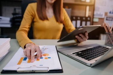 Tablet, kağıt ve dizüstü bilgisayarla masa başında çalışan iş kadını 