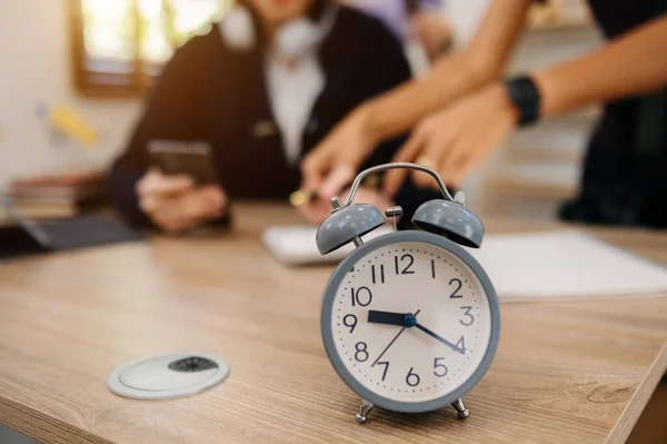 Alarm clock on desk. Business people working in office, blurred background with man and woman