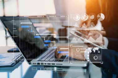 İş kolu proje yöneticisi çalışıyor ve görevleri güncelliyor ve Gantt grafik çizelgesi sanal diyagramını hazırlıyor.Ofiste akıllı telefon, tablet ve dizüstü bilgisayarla