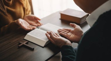 İncille ve haçla dua eden kadın ve erkeğin kesilmiş görüntüsü. 