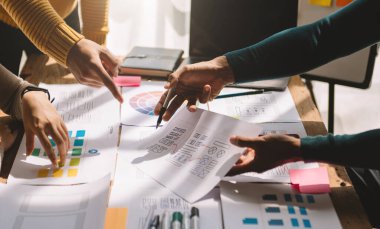 İş arkadaşları beyin fırtınası yapıyor. UX ajansı tasarımcıları masadaki web arayüzü tasarım projesi üzerinde çalışıyorlar