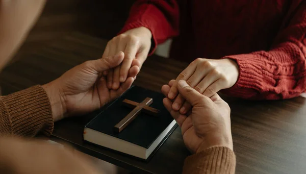 stock image man and woman holding hands. cross and bible book on table 