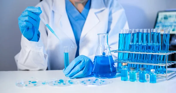 woman biotechnologist testing blue chemical substances in laboratory. covid-19 analytics