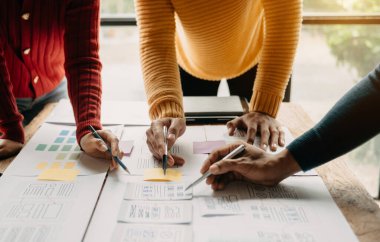  UX developer and ui designer brainstorming about mobile app interface wireframe design with customer brief and color code at office