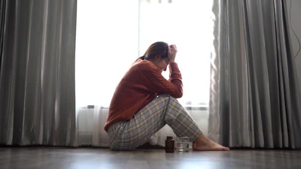 悲しみの女性が窓の近くの家で床に座っている — ストック動画
