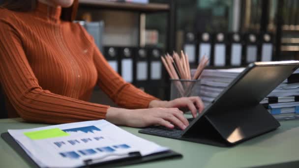 デジタルタブレットキーボードに入力するビジネス女性の部分的なビュー 机の上に統計資料があるフォルダ — ストック動画