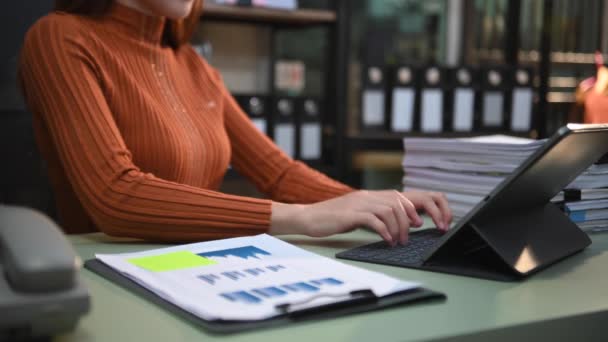 デジタルタブレットキーボードに入力するビジネス女性の部分的なビュー 机の上に統計資料があるフォルダ — ストック動画