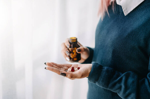 woman holding bottle with pills on hand going to take medicament prescribed by his physician doctor
