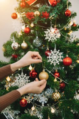 Young woman's hands decorating Christmas tree indoors. New year celebration