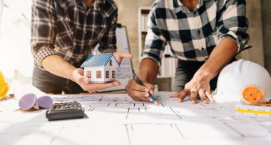 İki mimar ofiste modellik yapıyor. Masada planlarıyla birlikte. 