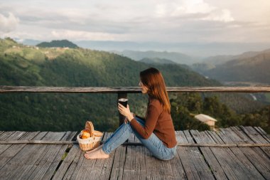 Rear view image of a female traveler sitting and looking at a beautiful mountain,field and nature view