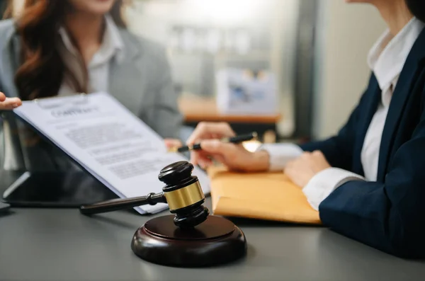 law hammer on table. lawyer discussing contract papers with client. people sitting at desk in office