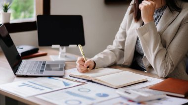 businesswoman working notes, modern computer and strategy diagram on table