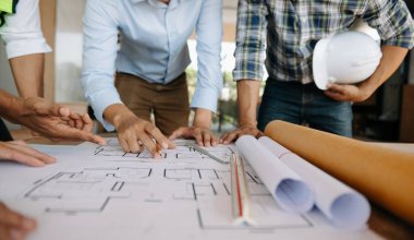 Creative architect projecting on the big drawings in the dark loft a building industry construction site