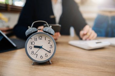 Alarm clock on the desk. Business working in office building or home at night using laptop. and smart phon