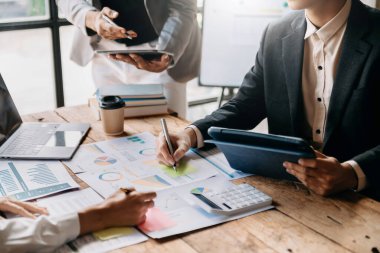 İş ortakları yeni bir başlangıç projesinde belge ve fikirleri akıllı telefon ve dijital tablet ve grafik işiyle tartışıyor. Finans görevi.