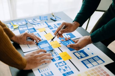  UX geliştiricisi ve ui tasarımcısı modern ofiste müşteri özeti ve renk kodu ile mobil uygulama arayüzü kablo tasarımı hakkında beyin fırtınası yapıyorlar