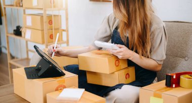  Woman hands using  tablet and writing notebook at the office of her business online shopping. In home office 