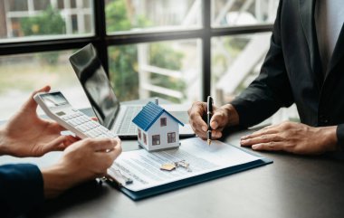 Emlak komisyoncusu, emlak kredisi teklifiyle ilgili sözleşme imzalama anlaşmasını, ev modelini sunar ve müşteriye danışmanlık yapar.