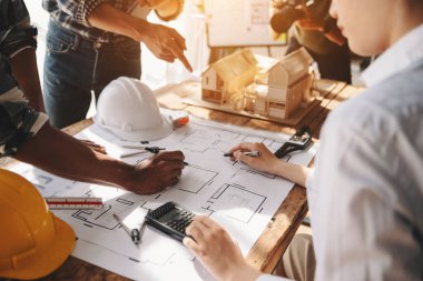  colleagues discussing data working  on architectural project at construction site at desk in office