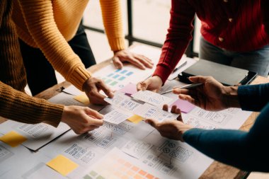 Close up view of UI developer team brainstorming on their project with laptop, smartphone and digital tablet. Creative digital development agency. at office