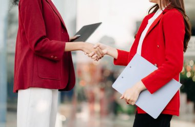 Two confident businesswomen shaking hands during a meeting in the office, success, dealing, greeting and partner in sunlight