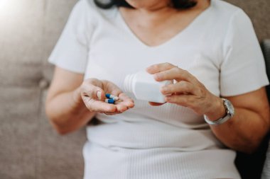 Old woman with glass of water and pills on hand going to take medicament prescribed by his doctor