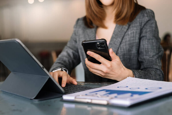 Уверенная деловая женщина, работающая на ноутбуке и планшете на своем рабочем месте в современном офисе