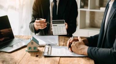 Real estate broker agent presenting and consult to customer to decision making sign insurance form agreement, home model, concerning mortgage loan offer