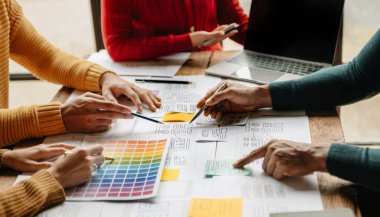 UX developer and ui designer brainstorming about mobile app interface wireframe design with customer brief and color code at office.