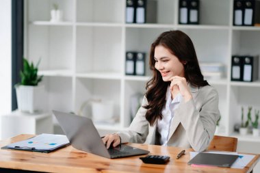 Asian female university student concentrating on her online classroom with tablet and laptop at office