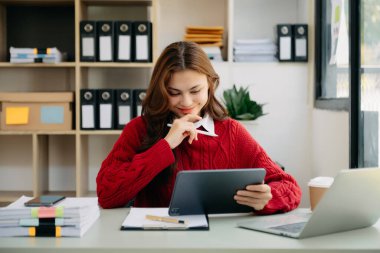  Beautiful Asian business woman typing laptop and tablet Placed at the table at the office