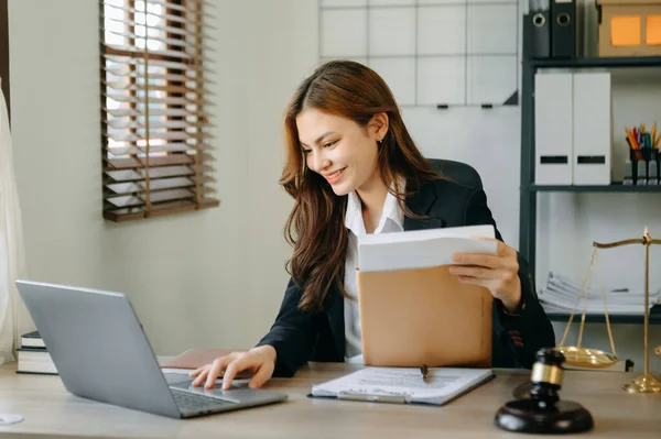 Attractive young lawyer in office. Business woman and lawyers discussing contract papers laptop and tablet with brass scale on  desk in modern office. Law, legal services, advice,