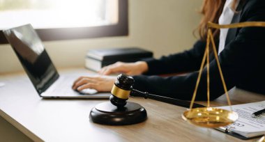 woman lawyer in the office with brass scale and using tablet and laptop on wooden table. justice and law concept in morning light