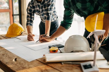 Two colleagues discussing data working  with on  architectural project at construction site at desk in modern office