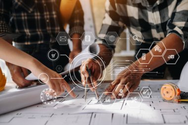 Two colleagues discussing data working and tablet, laptop with on on architectural project at construction site at desk in modern office