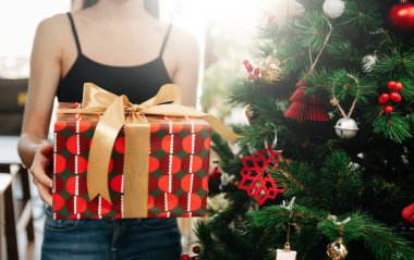 Mutlu Noeller! Yılbaşı hediyeli eller ve arka planda kırmızı kurdeleli ışıklar. Şenlik odasında. Kapatın. Mutlu Noeller.