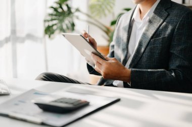 Confident businessman working on tablet at workplace at modern office