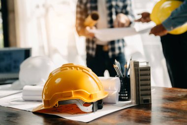 Engineer desk with object paper and tablet with blurry engineer teamwork hardworking to consults about their building project. in office